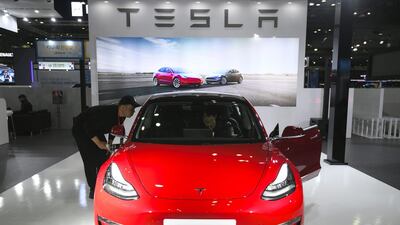 Visitors look at a Tesla Model 3 at the show. Jung Yeon-Je / AFP