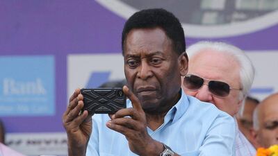 Pele takes a photograph with his phone during the Subroto Cup final in New Delhi on Friday. Rajat Gupta / EPA