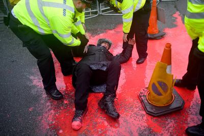 Police arrest a protester for throwing red paint on the ground in support of WikiLeaks founder Julian Assange. Getty