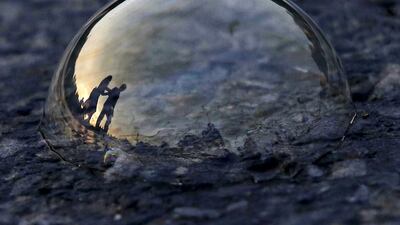 People are reflected on a soap bubble lying on a road during an evening in New Delhi. Anindito Mukherjee / Reuters