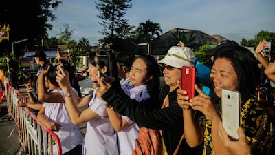 Onlookers watch and cheer as a helicopter flies towards an airstrip near Tham Luang Nang Non cave to transport the fifth boy rescued from the cave to hospital. Getty Images