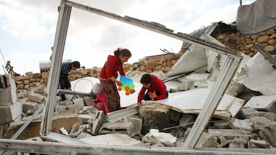 Palestinian children search for toys in the remains of their home in Jinba after it was demolished by Israeli bulldozers on February 2, 2016. Hazem Bader/AFP