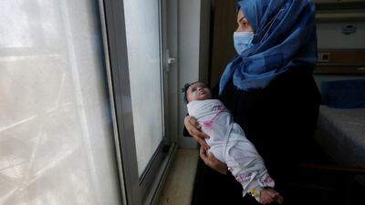 An Iraqi woman wearing a protective mask carries her baby who suffers from cancer at the Children's Hospital for Cancer Diseases, amid the spread of the coronavirus disease in Basra. Reuters