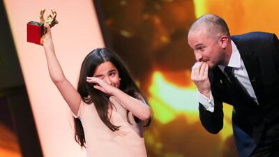 Hana Saeidi, left, holds up the Golden Bear for the movie Taxi, which she accepted on behalf of Iranian director Jafar Panahi, next to the American director Darren Aronofsky, at the annual Berlin International Film Festival. Michael Kappeler / EPA
