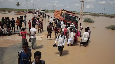 Families walk on a flooded road after heavy rainfall in the village of Aboud in the Al Manaqil district in Al Jazeera state south of the Sudanese capital, Khartoum. AP