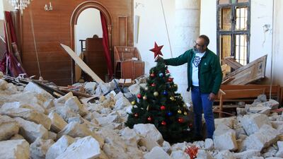 A man sets up a Christmas tree amid the rubble of the Melkite Church, which was hit by an Israeli air strike on October 9, in the southern Lebanese village of Derdghaya. AFP