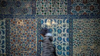 A woman passes next to a tile wall at Eyup Sultan Mosque in Istanbul. Ozan Kose / AFP Photo