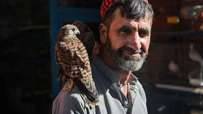 A bird vendor poses with two kestrels as he waits for customers in the Ka Faroshi bird market in Kabul on July 16, 2022. (Photo by Lillian SUWANRUMPHA / AFP)