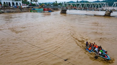 Residents are ferried across a river after a bridge was damaged by flooding in Juli, in Indonesia's Aceh province. AFP