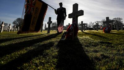 John McCarthy from the Royal British Legion pays his respects at the grave of Sergeant Maurice Robbins at the Cambridge American Cemetery in Coton, England. PA via AP