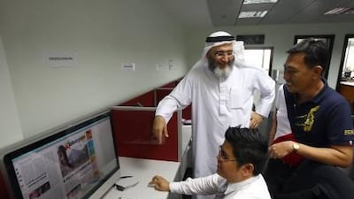 Atallah Habib, left, the owner and publisher of Kabayan Weekly, talks to editor-in-chief, Camcer Ordonez Imam, right, and designer Mohamed Manampan, seated, at their office in Dubai.