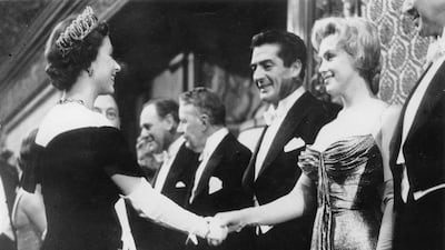 US actress Marilyn Monroe and actor Victor Mature meet the British monarch at the Empire Theatre in London. Getty
