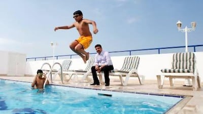 Nevil Jacob, 9, (left) and his brother Emil Jacob, 11, swim at their Oud metha apartment pool while their father, Jacob Mathew, supervises. Sarah Dea/The National