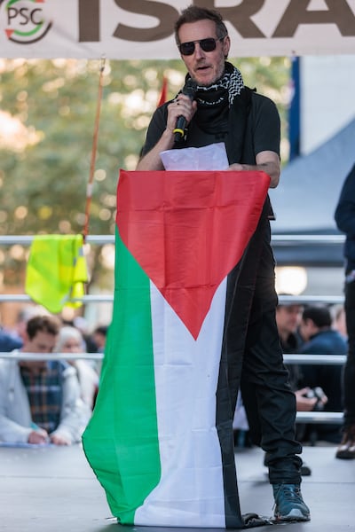 Musician Robert Del Naja holds a Palestinian flag on stage during a March for Palestine in October 2025. Getty Images