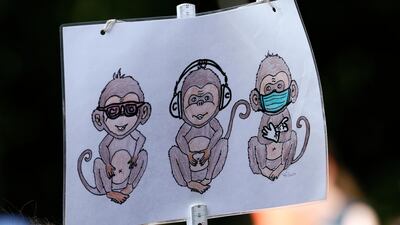 A placard displays the three wise monkeys pictorial maxim with a sanitary mask during a protest against coronavirus pandemic regulations in Berlin, Germany. EPA