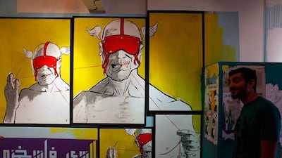 Egyptian street artist Ghanzir walks by a mural with Arabic that reads 'the people are giving me a hard time,' inside an art exhibition of street graffiti.