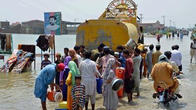 People jostle for drinking water delivered by a municipality lorry along a flooded road in Sohbatpur, Balochistan. AP