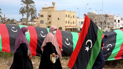 A woman in Tripoli carries a Libyan flag during celebrations to mark the 10th anniversary of the 2011 uprising that led to the downfall Muammar Qaddafi. AFP