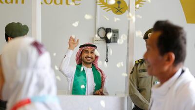An airport worker throws flowers as he welcomes Malaysian pilgrims at the Hajj Terminal at Jiddah airport, Saudi Arabia. AP Photo