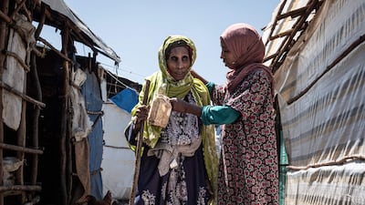 A woman from Ethiopia's Amhara community helps her blind mother walk at the Bakelo Camp for internally displaced people. AFP