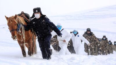 This photo taken on February 19, 2020 shows police officers wearing protective face masks walking with horses on their way to visit residents who live in remote areas in Altay, farwest China's Xinjiang region, to promote the awareness of the virus. The death toll from China's new coronavirus epidemic jumped to 2,112 on February 20 after 108 more people died in Hubei province, the hard-hit epicentre of the outbreak. - China OUT / AFP / STR