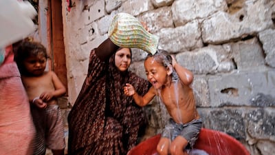 A Palestinian mother gives her children a bath amid a heatwave during the ongoing pandemic crisis in Gaza City. AFP