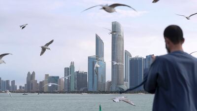 A resident feeds seagulls on the Abu Dhabi Corniche. Khushnum Bhandari / The National