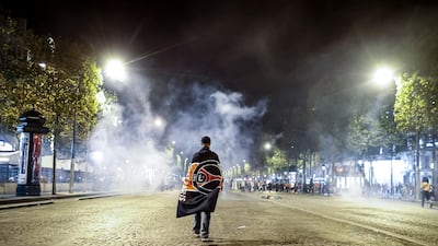A Paris Saint Germain supporter walks through a cloud of teargas on the Champs Elysees. EPA