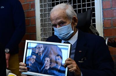 Holocaust survivor Leon Schwarzbaum with a family picture as he arrives to observe a trial against defendant Josef Schuetz. AFP
