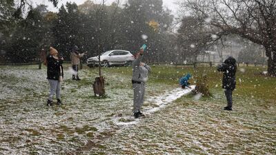 People take photos as snow falls in Zoo Lake park in Johannesburg. AFP