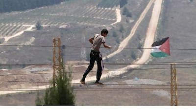 A man practices walking on ropes near a set flag at Iran Garden, the park developed by an Iranian organisation that faces an Israeli settlement, seen in the background, in the border village of Maroun el Rass, Lebanon. Mohammed Zaatari / AP Photo