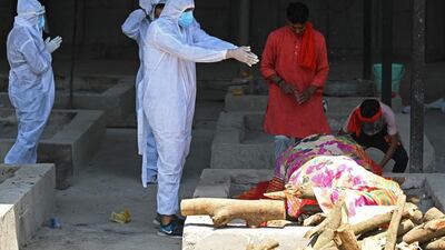 A family member wearing protective gear performs the final rites of a coronavirus victim at a crematorium in New Delhi. AFP