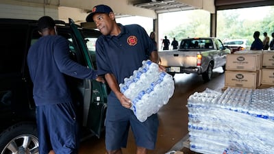A Jackson Fire Department firefighter puts cases of bottled water into a resident's car as part of the city's response to water system problems. AP