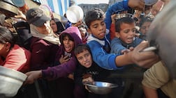 Displaced Palestinians gather to receive food at a charity kitchen in Gaza's Nuseirat refugee camp on December 20. For many, their only lifeline is international aid. AFP
