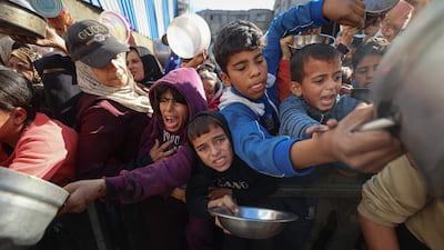 Displaced Palestinians gather to receive food at a charity kitchen in Gaza's Nuseirat refugee camp on December 20. For many, their only lifeline is international aid. AFP