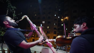 Egyptians Mahmoud Saad (left) plays saxophone and Mohamed Adel (right) violin on their balcony during curfew in Giza, Egypt. EPA