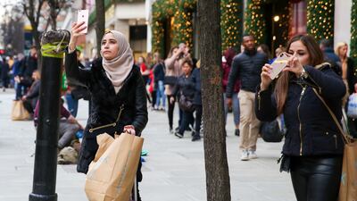 A Muslim woman with shopping bags takes a selfie with Oxford Street Christmas decorations in London. Getty Images