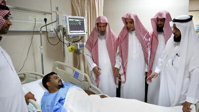 Sheikh Al Faleh, centre, deputy director of the Prophet’s Mosque, and others visit an injured man. Saudi Press Agency via AP