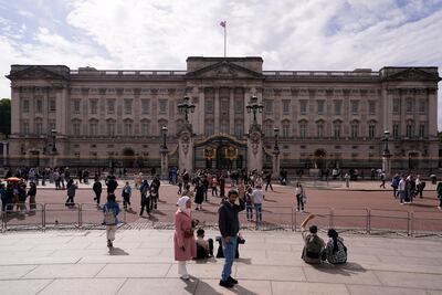 Tourists take photos and visit Buckingham Palace in London. AP