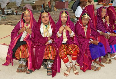 Omani girls in colourful traditional dress take a break during a cultural festival in Muscat, in the Sultanate of Oman. Alamy