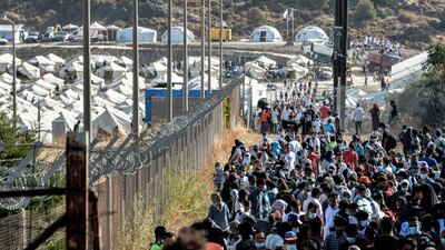 Migrants most of them, wearing face masks against the spread of the new coronavirus, gather outside the temporary refugee camp in Kara Tepe as they wait to depart from Lesbos for mainland Greece AP