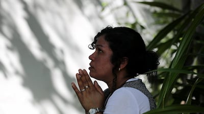 A woman holds her hands in prayer at the bodhi tree just outside the temple. Chris Whiteoak / The National