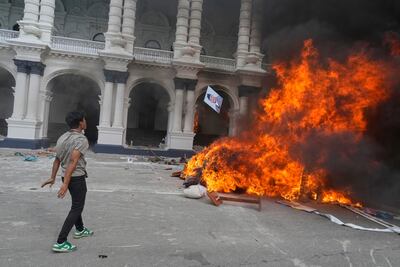 A protester throws a photo of Nepal Prime Minister KP Sharma Oli in a fire at the Singha Durbar, the seat of Nepal's government ministries and offices in Kathmandu. AP