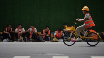 Construction workers eat their lunch on the roadside near office buildings in Beijing's central business district. AP