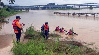 Rescue workers search for a missing firefighter who was swept away in a flash flood, caused by heavy rain, in Chungju, South Korea. EPA