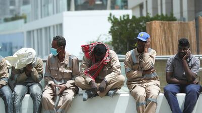 Workers protect themselves from gusty winds at the Al Raha creek area in Abu Dhabi. Victor Besa / The National
