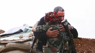 In this image made from a video taken in late November, 2014, Kurdish fighter Pervin Kobani, 19, and her father, Farouk, embrace in Kobani, Syria. Jake Simkin via AP video