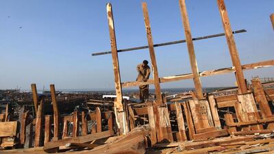 A carpenter uses manual tools to cut out a wood panel while working on a boat at a yard in Karachi's Fish Harbour. Akhtar Soomro / Reuters