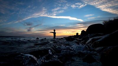 Rick Yen is silhouetted as he casts a rod while fishing for salmon near the mouth of the Capilano River off Ambleside Park at sunset in West Vancouver, British Columbia. Darryl Dyck / The Canadian Press via AP