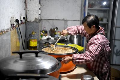 This photo taken on November 29, 2020 shows Wen Junhong preparing dog food at a home for rescued animals in Chongqing, southwestern China. Twenty years ago, Wen Junhong saved an abandoned dog from the streets of Chongqing in southwestern China. She now shares her home with more than 1,300 of them, and they keep on coming. - TO GO WITH AFP STORY CHINA-ANIMAL-RESCUE,FOCUS BY HELEN ROXBURGH AND QIAN YE / AFP / NOEL CELIS / TO GO WITH AFP STORY CHINA-ANIMAL-RESCUE,FOCUS BY HELEN ROXBURGH AND QIAN YE